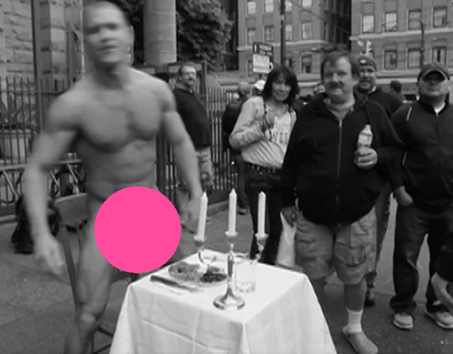 Un artista musculoso desnudo y come en medio de la calle