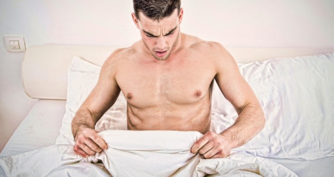 A man looks at his groin in bed - sexual health/STI