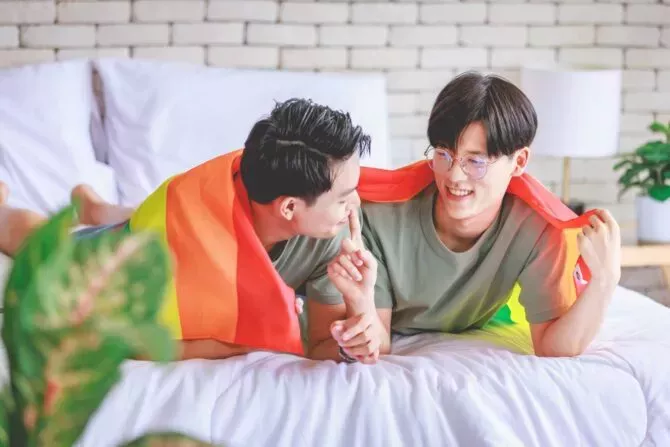 Gay couple cuddling under pride flag