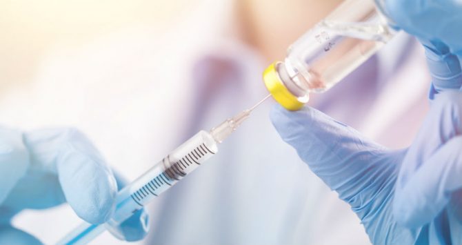 A health professional prepares an injection