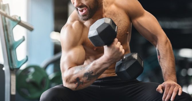 A bodybuilder flexes his biceps at a gym