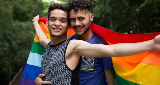 A gay couple hold a rainbow flag