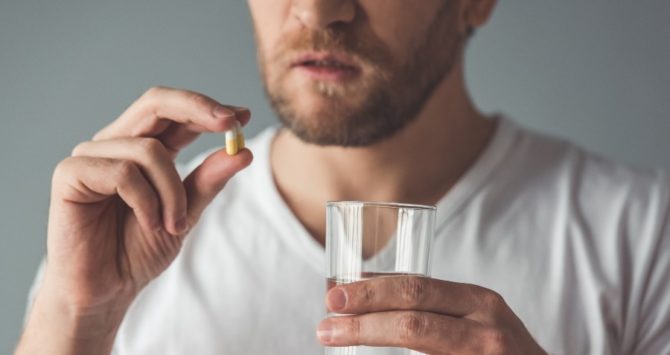 A man takes a tablet of medication
