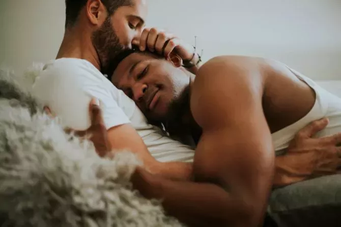 Two men cuddle and kiss