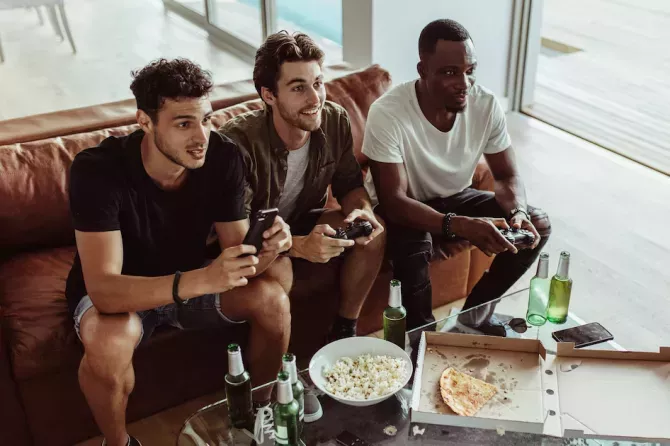 Guys playing video games on a couch