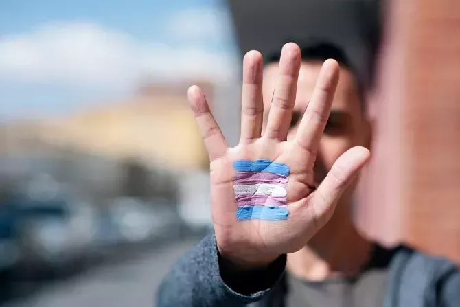 Closeup of the palm of the hand with a transgender flag painted in it