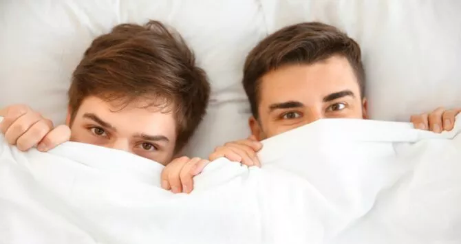 Two young gay men in bed together