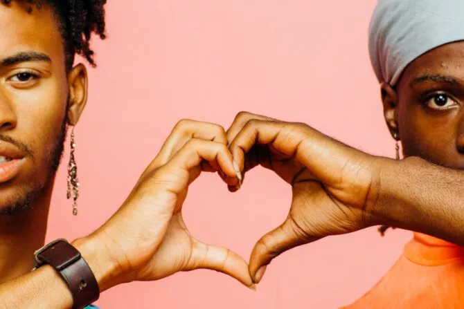 Two men hold their hands together to create a heart shape