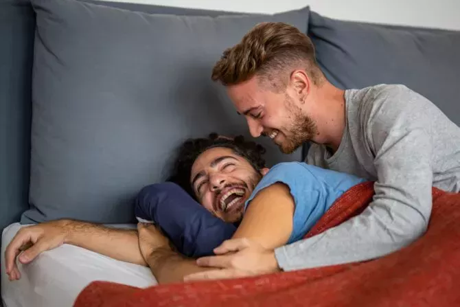 Happy male gay couple on bed at home
