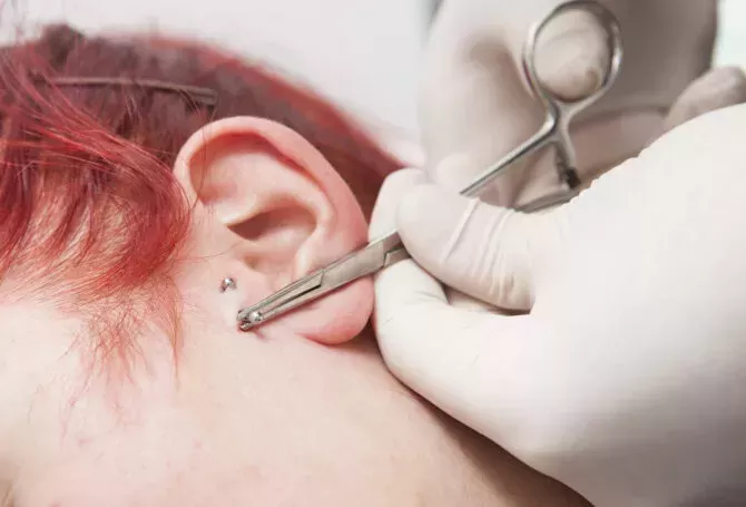 Professional placing the jewel of piercing on the ear with bal