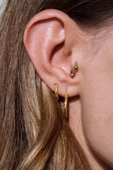 Close up of a woman's ear with multiple earrings