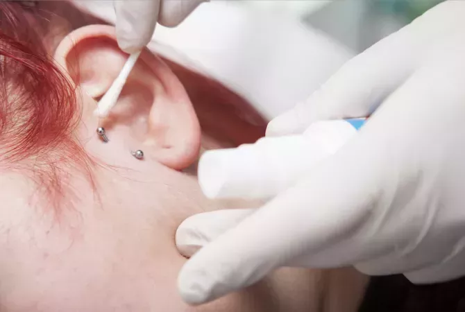 Professional cleaning the wound after piercing a young girl ear