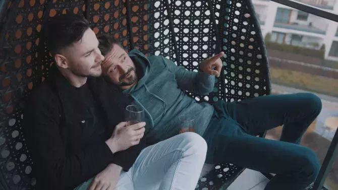 Gay couple drinking wine on a loveseat