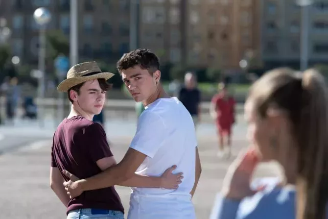 Gay angry teenager couple looking back to surprised woman