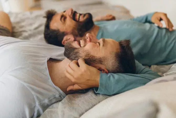 Happy gay couple lying down on the bed 