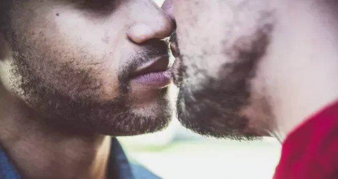 Two men lean in to kiss each other