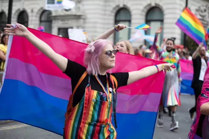 A person hods a bisexual pride flag at a gay pride march in London