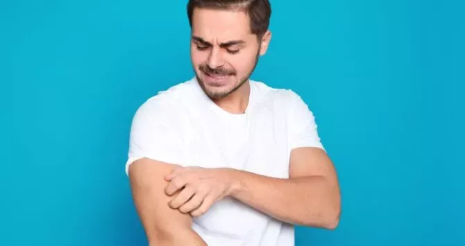 A man scratches his arm