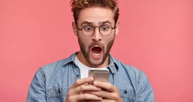 A shocked man looks at his cellphone