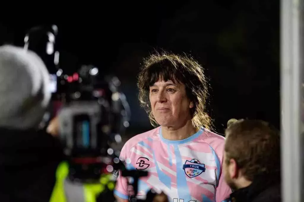 A photo of trans woman Paula Griffin in front of a camera after playing a match with her women's football team