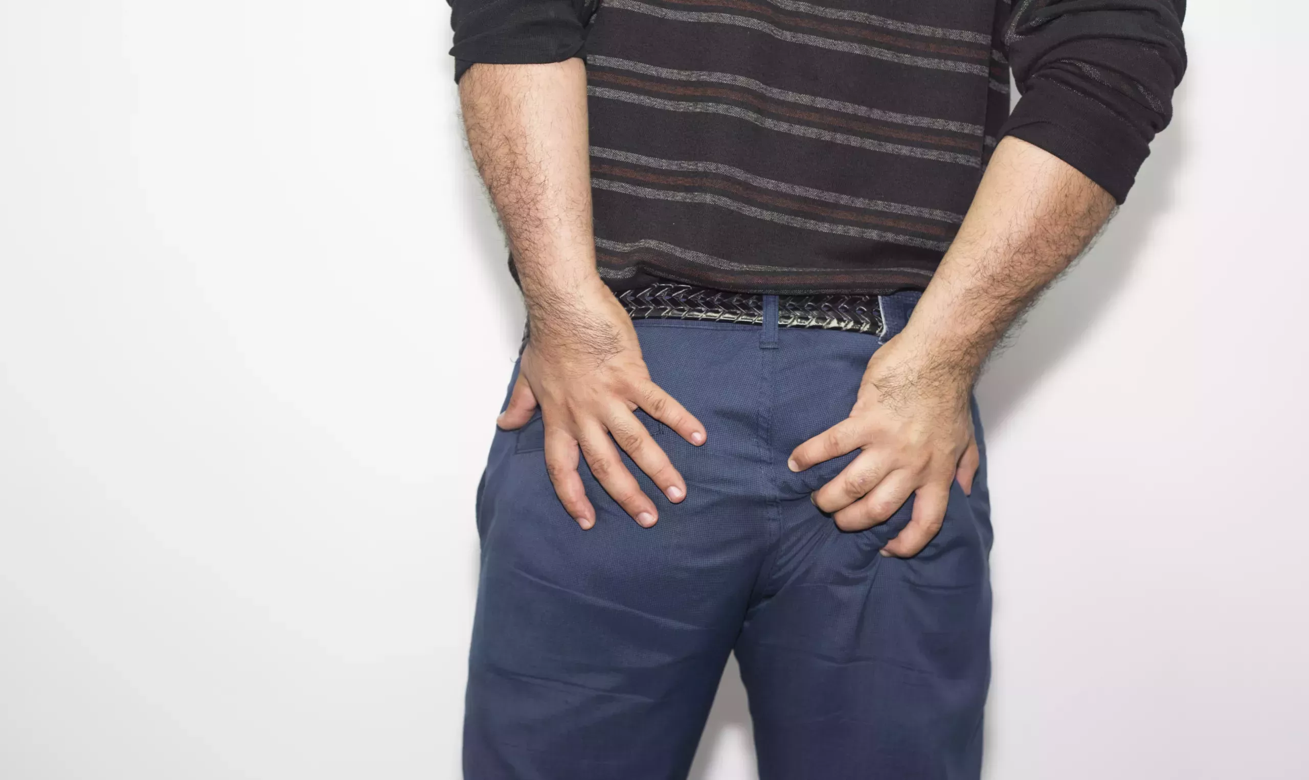 Man in blue pants grabbing his butt checks and squeezing.
