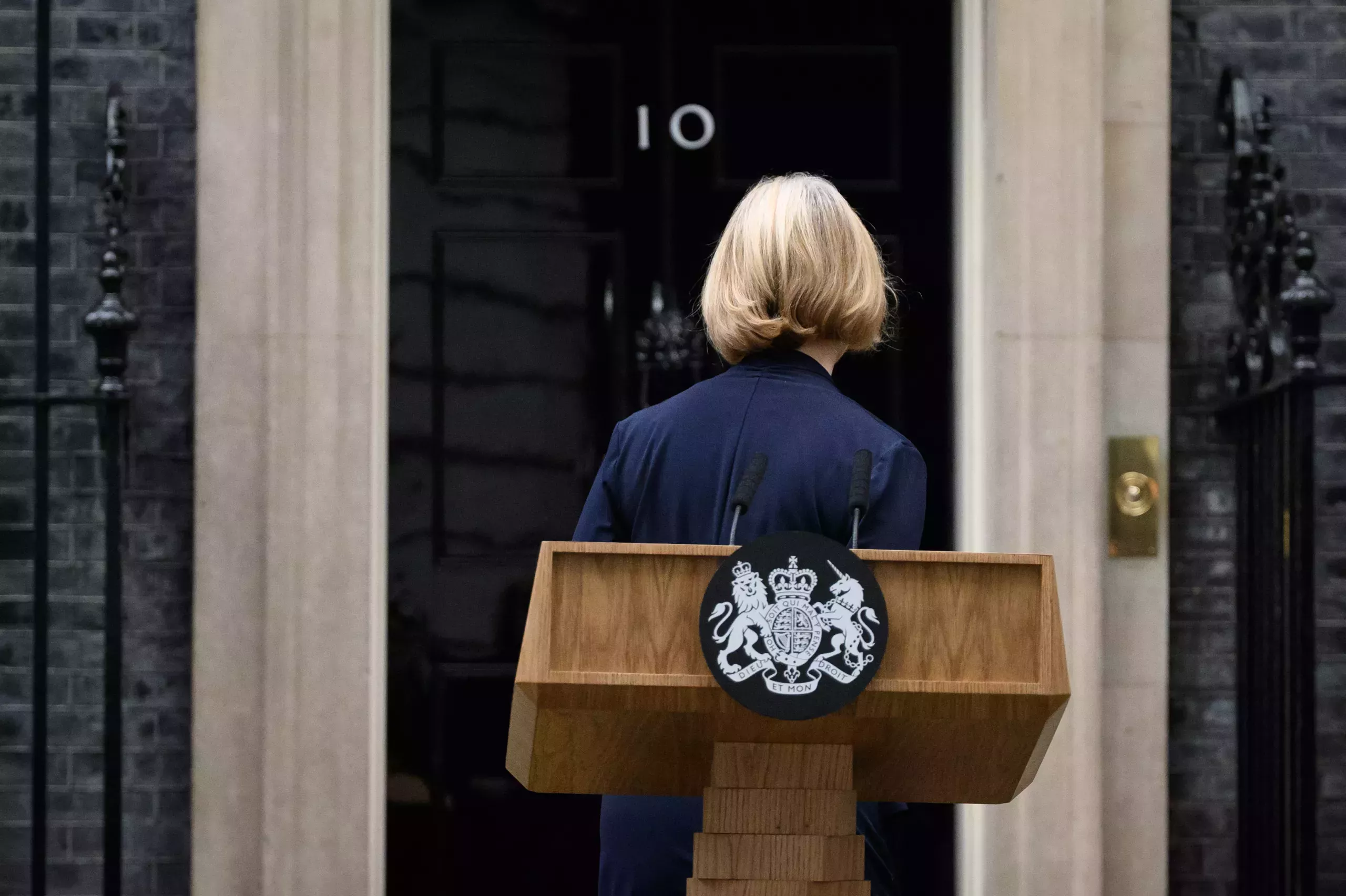 A shot of Liz Truss leaving her lectern in front of 10 Downing Street. Truss' back is turned to the camera.