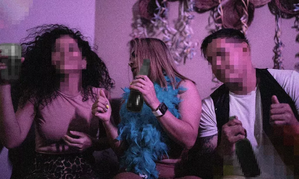 Photo of three people at a house party, holding bottles