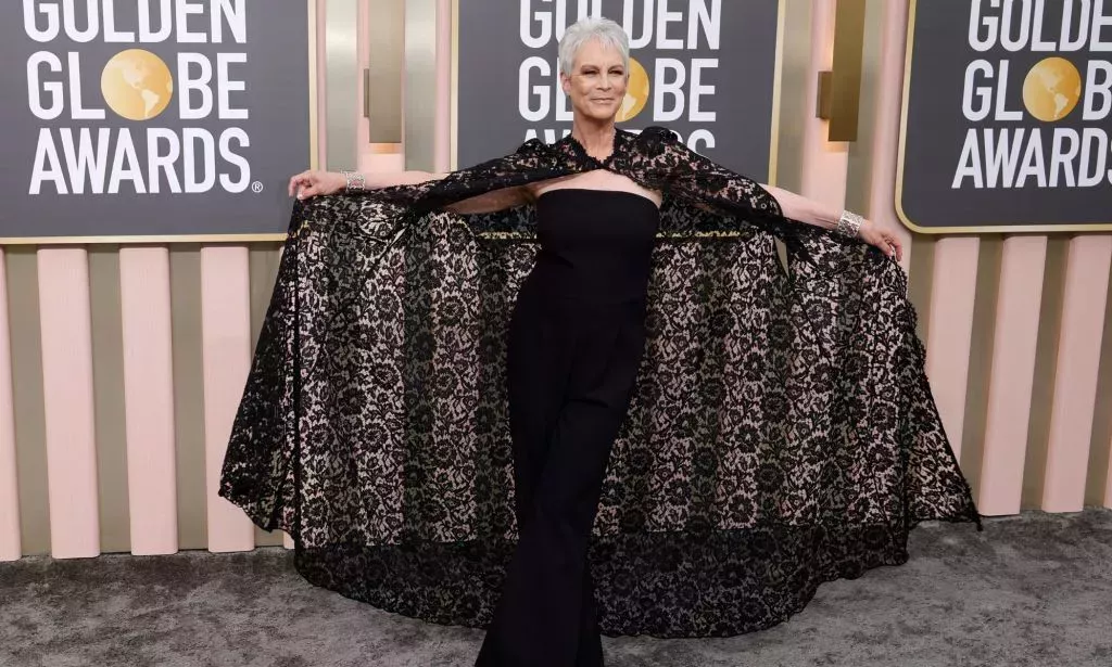 Jamie Lee Curtis in a purple gown and cape on the Golden Globes red carpet.