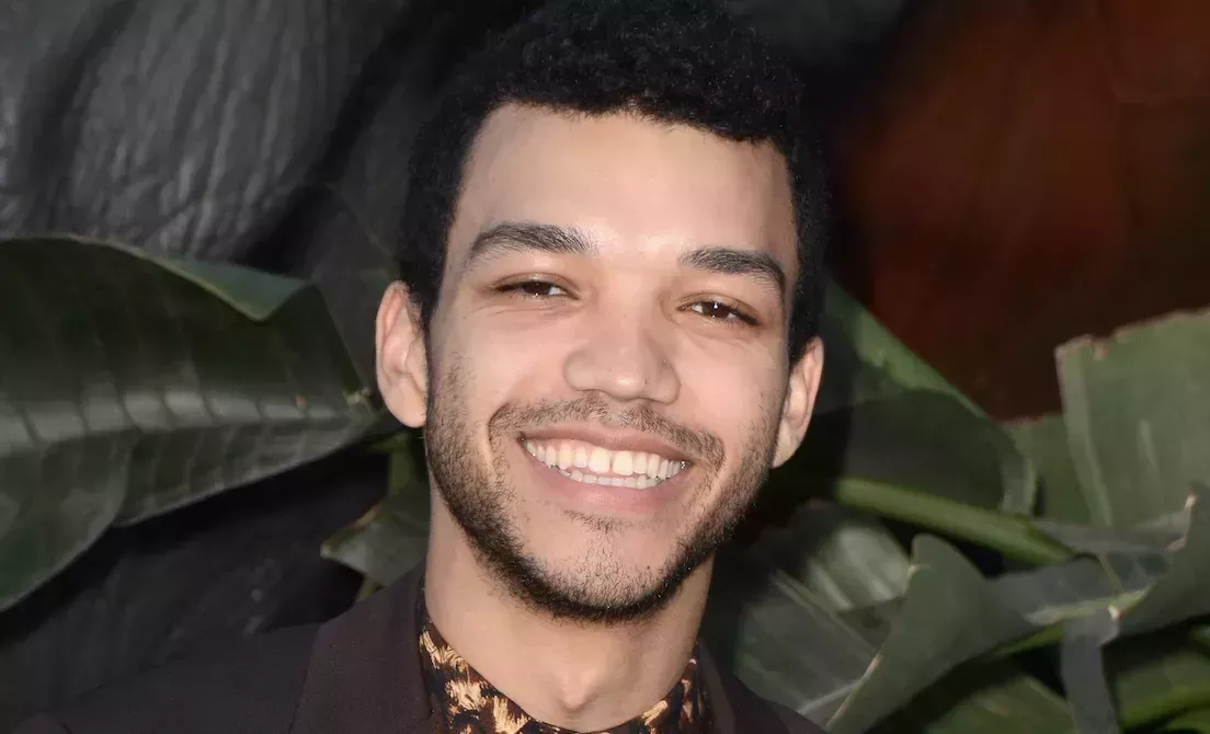 Justice Smith in brown suit, posing for camera