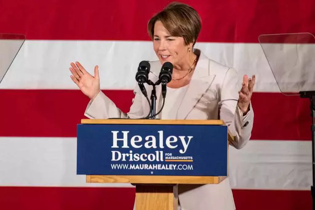 A photo of Democrat Maura Healey standing in front of the American flag as she talks into a microphone during her acceptance speech
