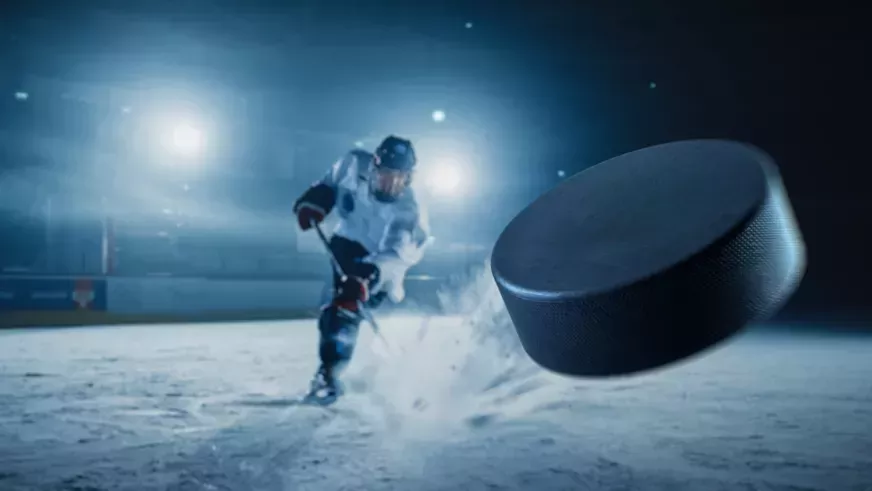 Hockey player hitting a puck on ice.