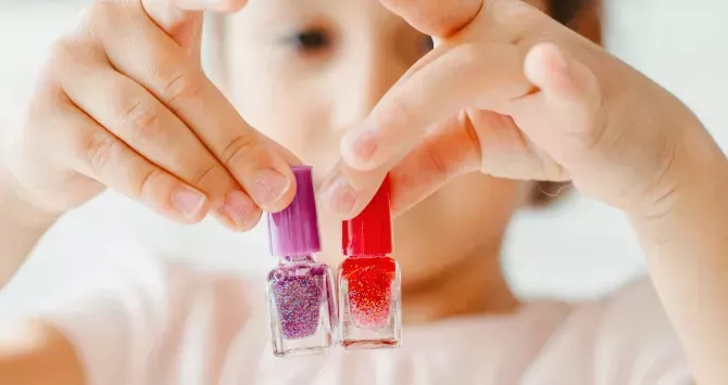A child holds up nail polish