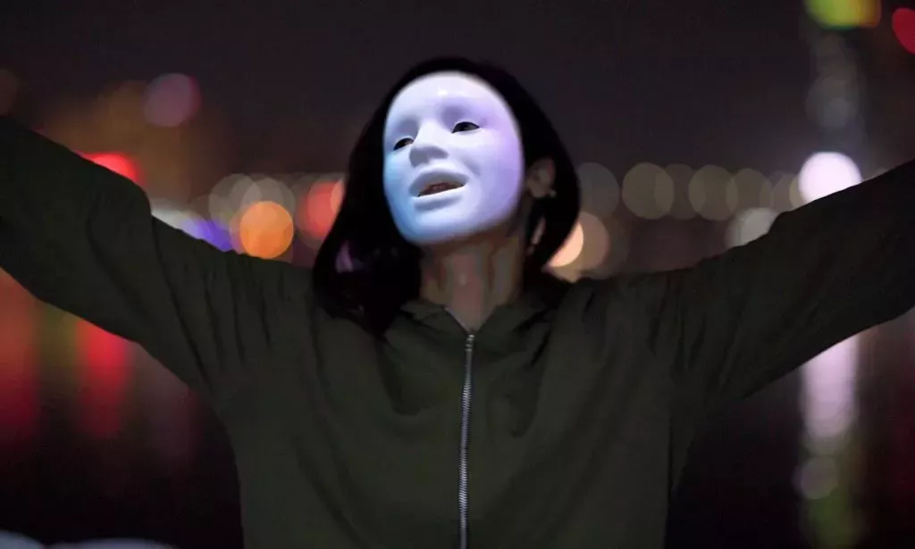 Laila, a trans person whose identity has been protected by masking technology, smiles and holds her arms out as she celebrates being able to escape LGBTQ+ persecution in Egypt