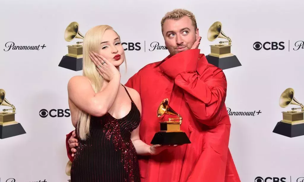 Kim Petras and Sam Smith pout and hold their Grammy award for "Unholy".