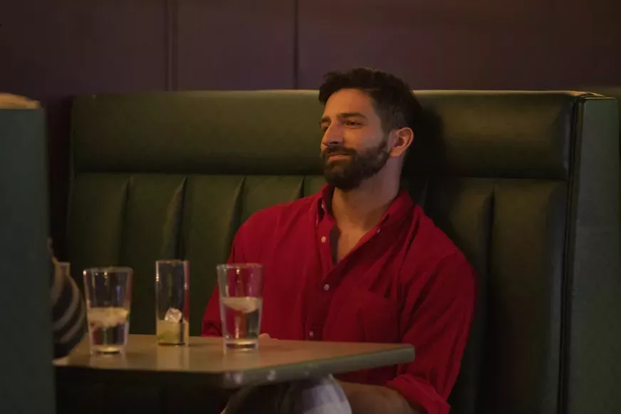 Kris from 'Swiping America' wearing a red shirt in a bar table.