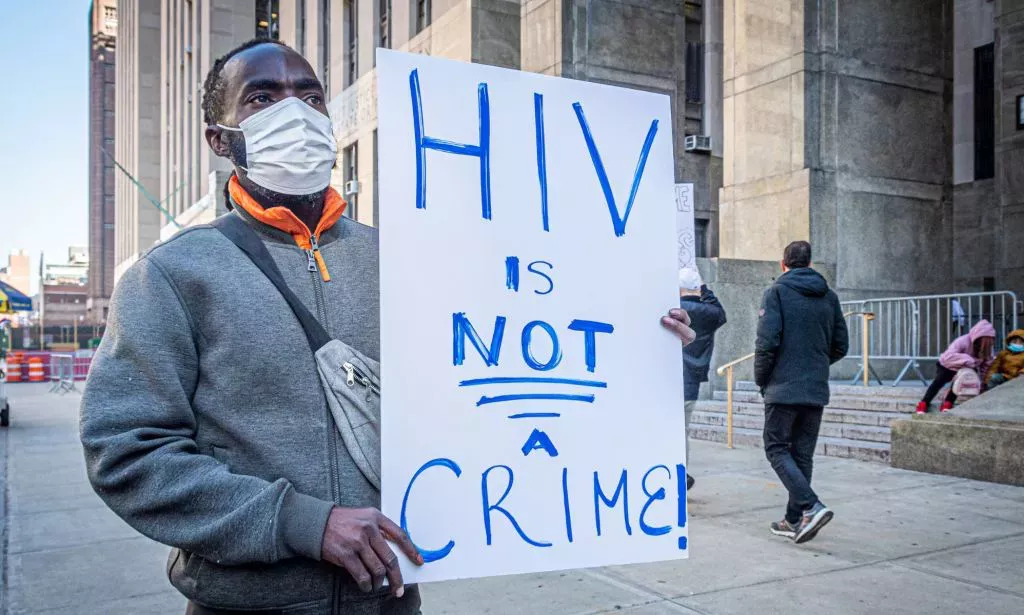 A man holds a sign reading "HIV is not a crime"