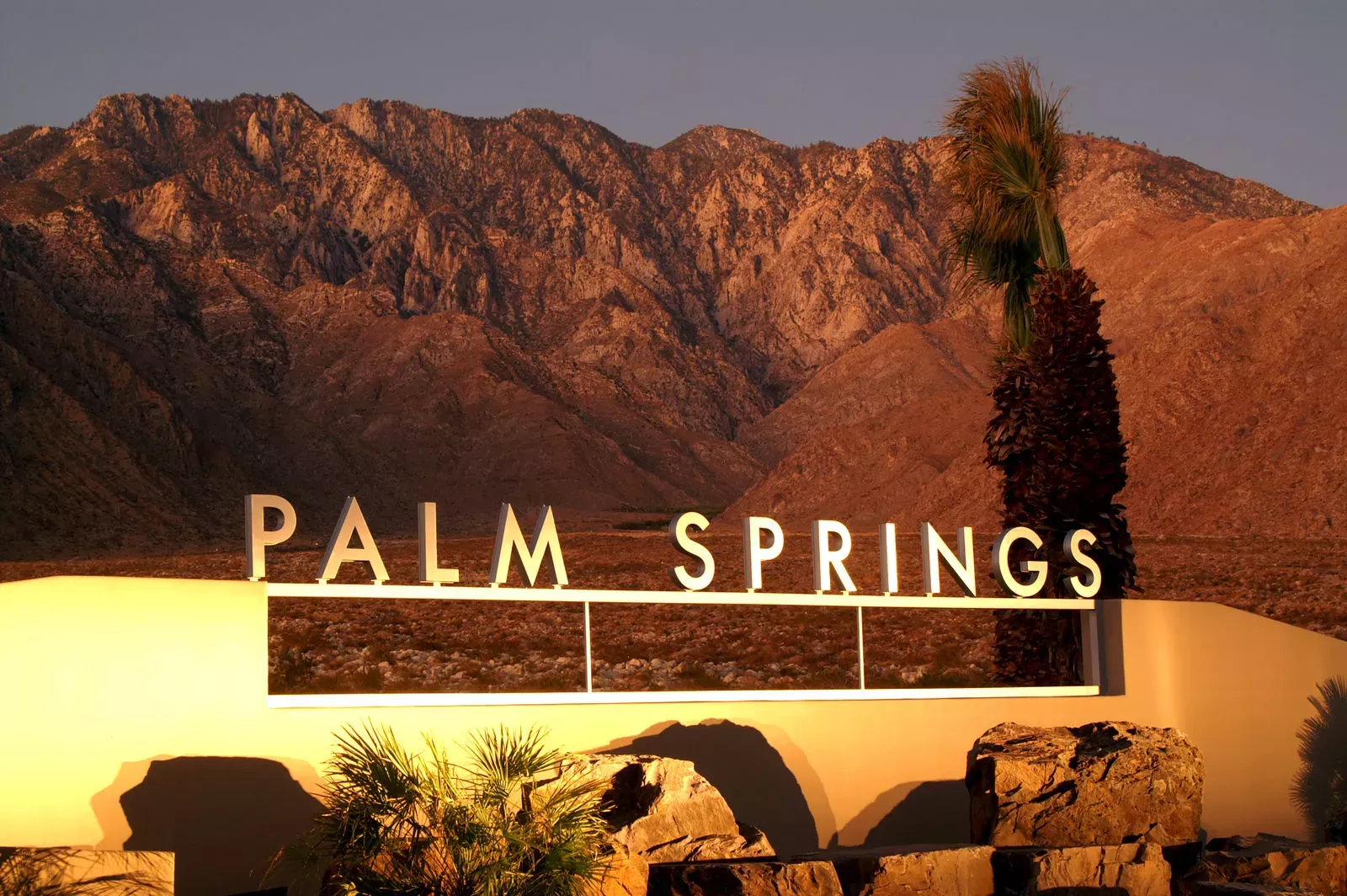 A sign of Palm Springs with a desert background. 