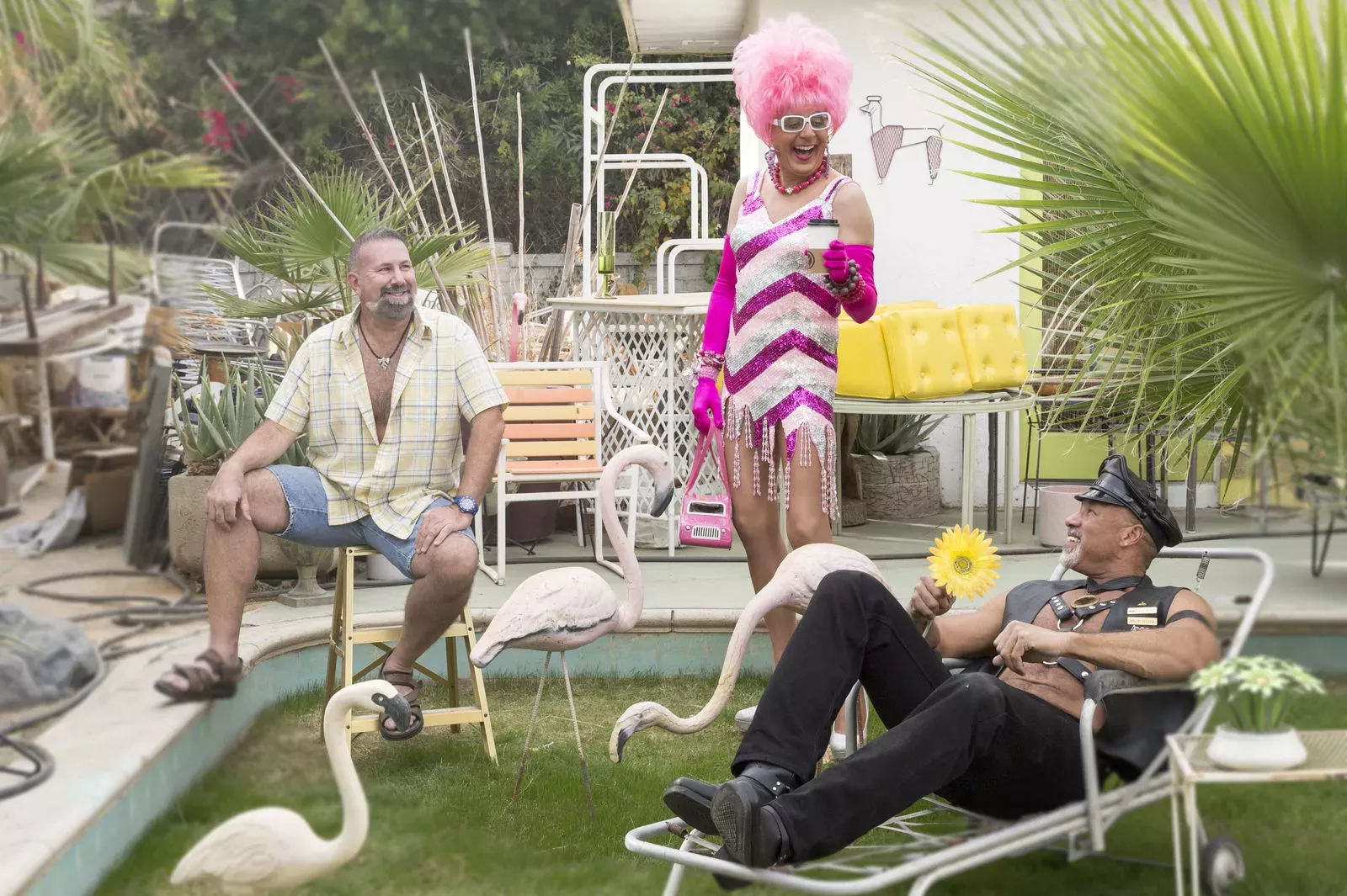A man, a leather daddy, and a drag queen having fun outside. 