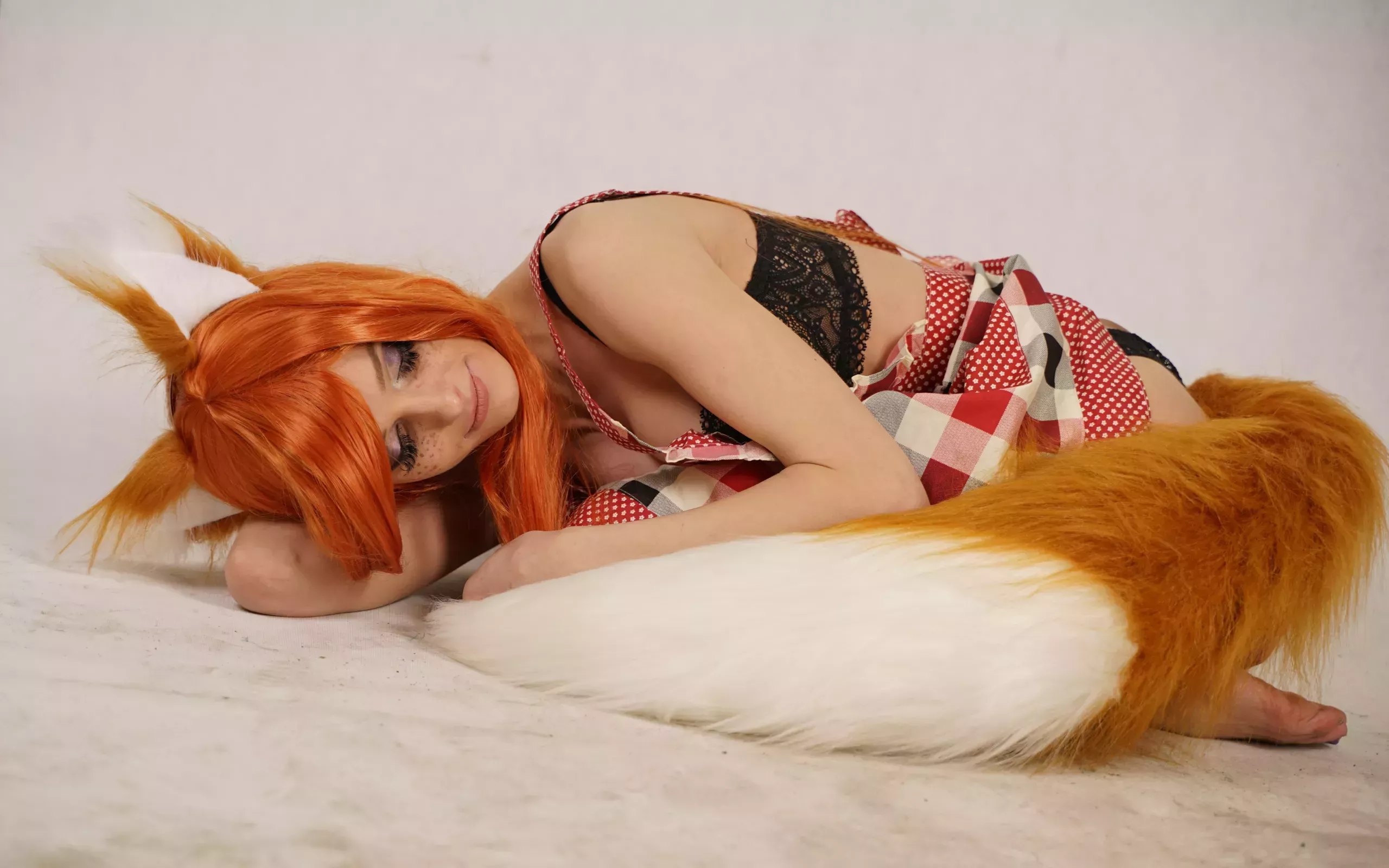 A woman cradling herself wearing fox ears and tail. 