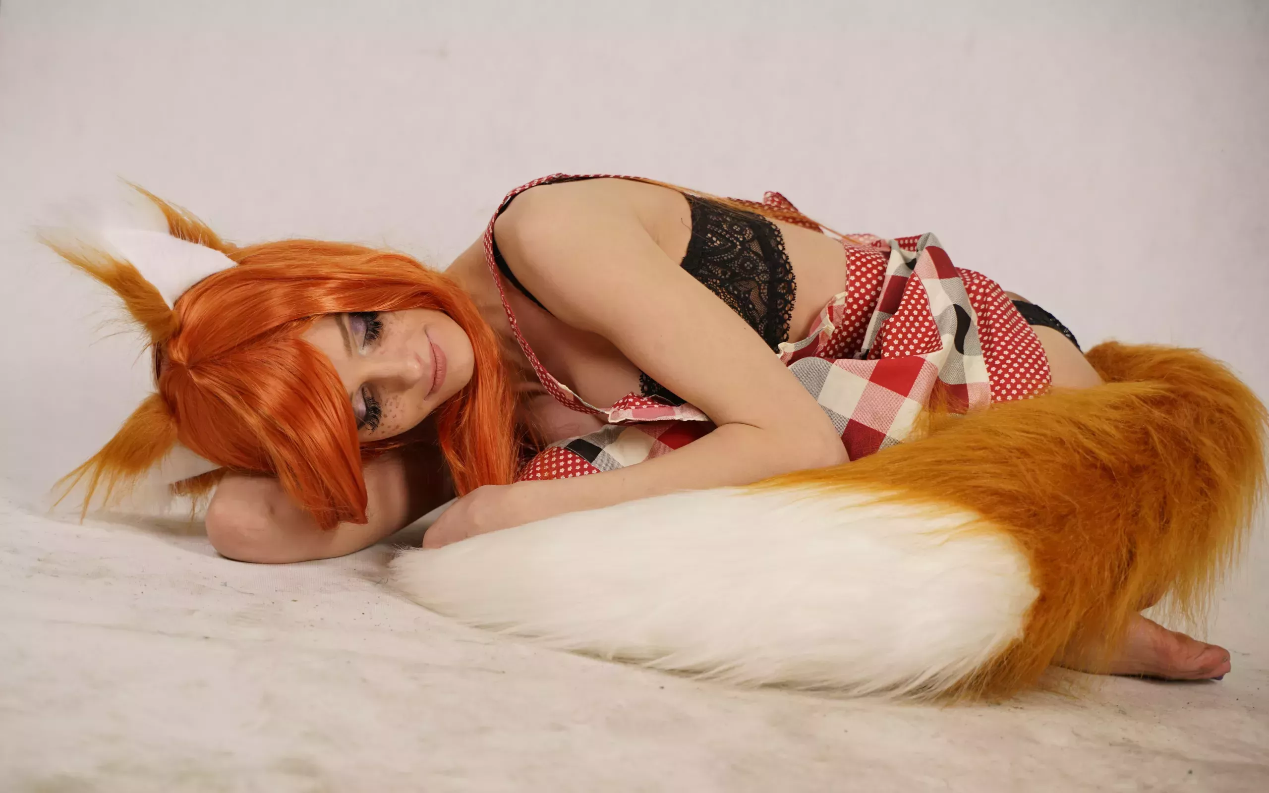 A woman cradling herself wearing fox ears and tail.