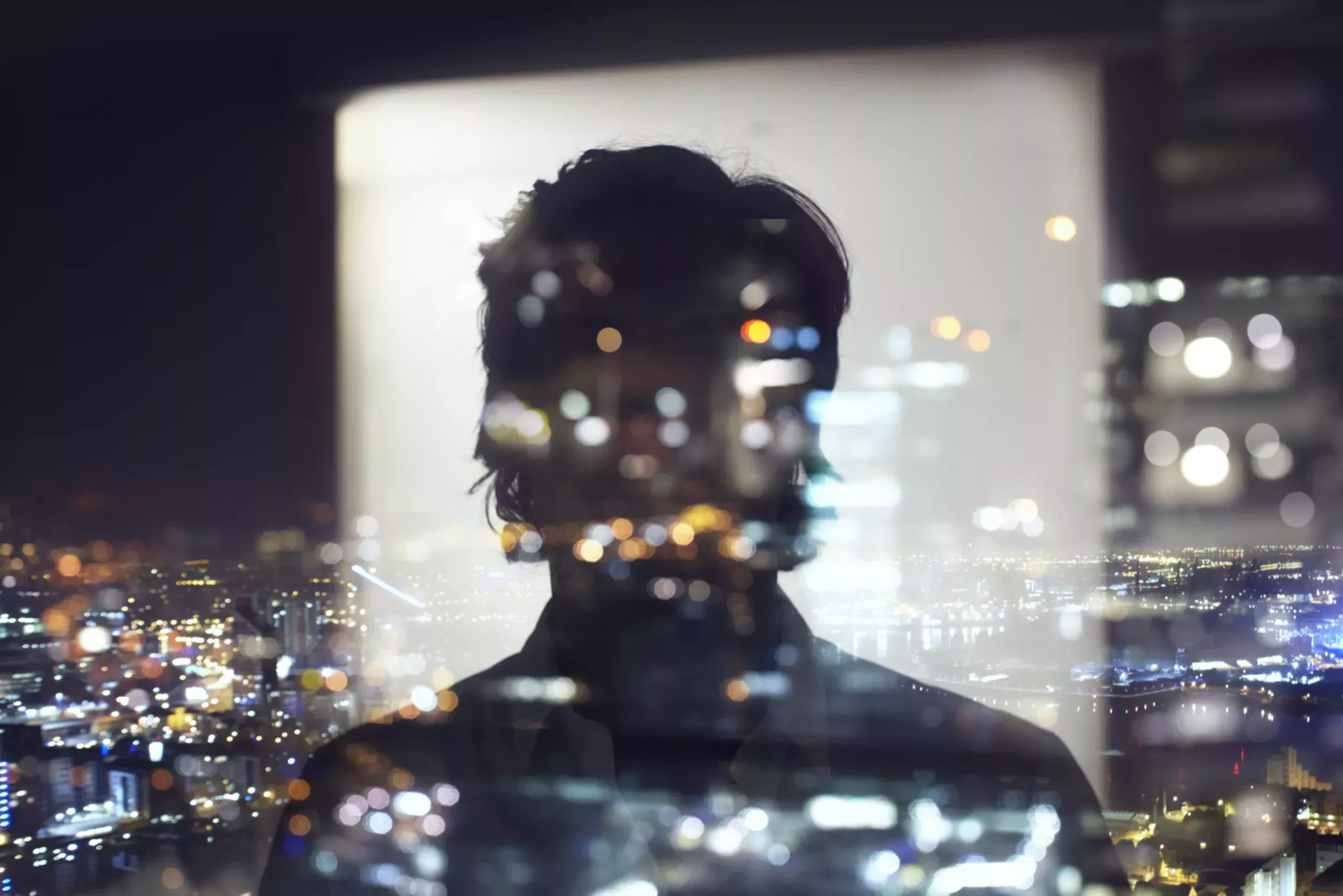 Man looking out at the city through a window.