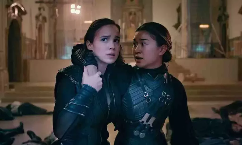 A still from Netflix series Warrior Nun showing actors Alba Baptista and Kristina Tonteri-Young as Ava and Beatrice wearing their warrior nun costumes; and Ava is supporting Beatrice in a room with bodies lying on the floor
