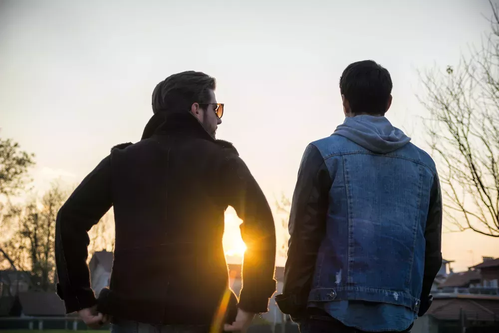 Two men talking in front of sunset