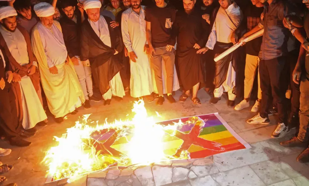Homophobic protestors in Iraq burn two Pride flags with X's drawn on them
