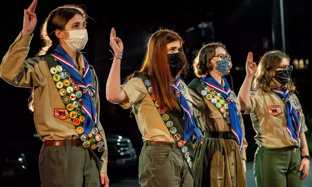 Girl members of the Boy Scouts of America stand in a line.