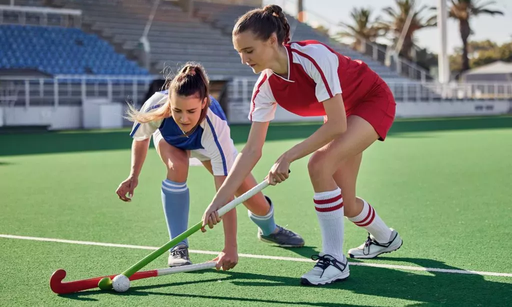 Dos mujeres compitiendo en un partido de hockey